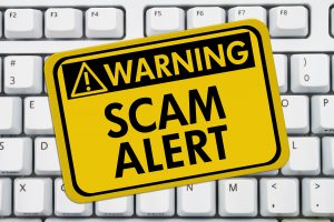 Computer keyboard keys with warning sign with words Scam Alert Scam Alert
